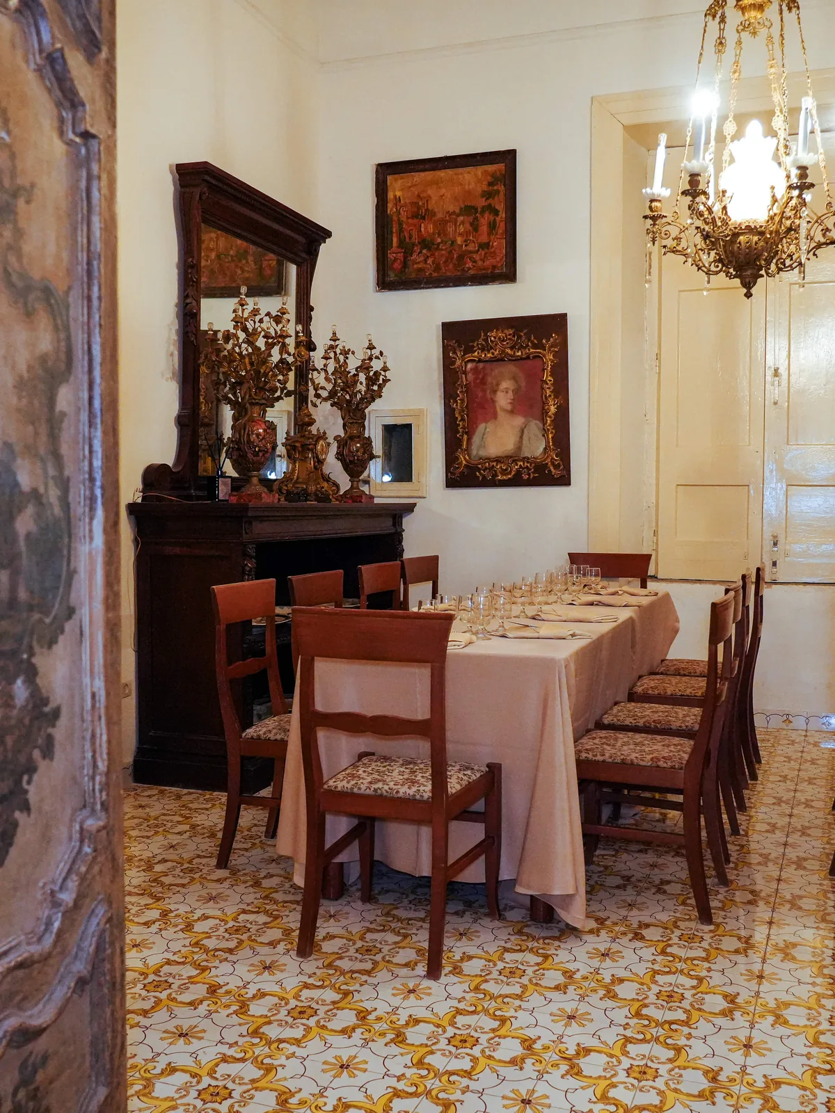 Sale in enfilade della Tenuta Don Gaetano, con la tavola apparecchiata vista da una porta dipinta a mano