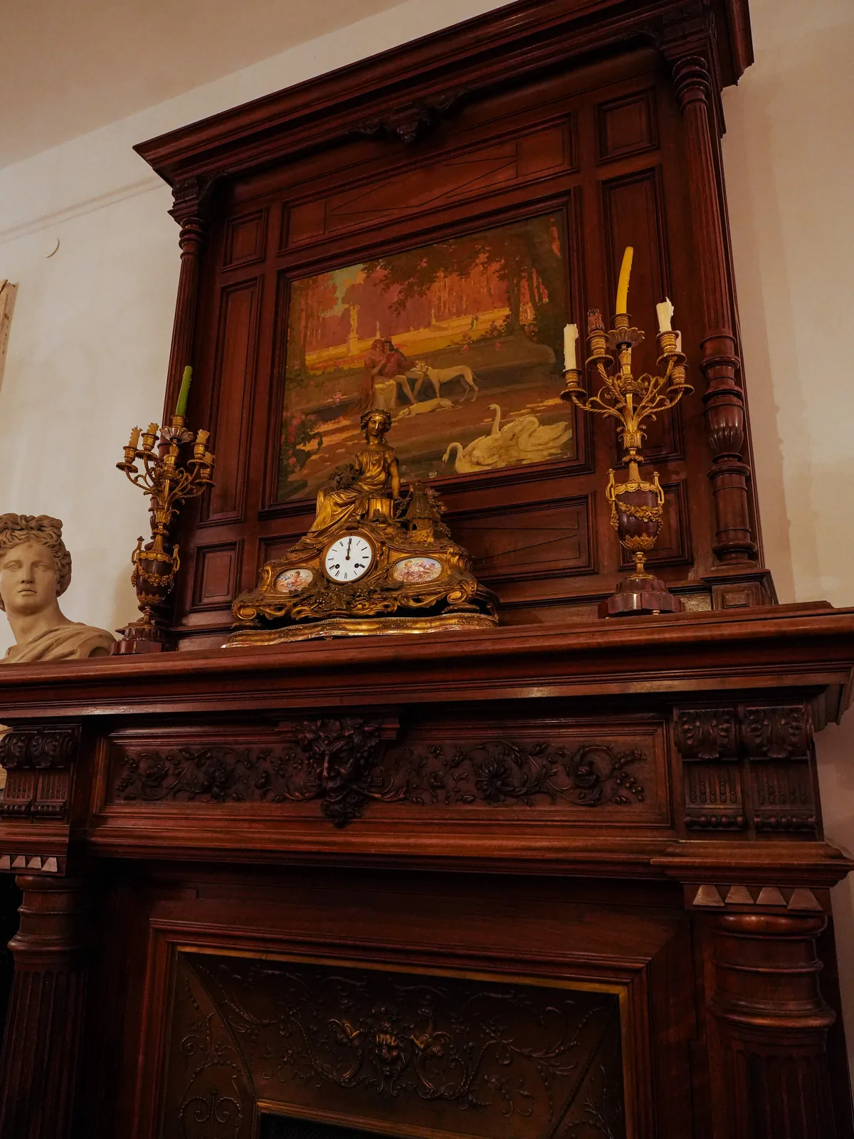 Camino monumentale in legno intagliato con orologio dorato e candelabri