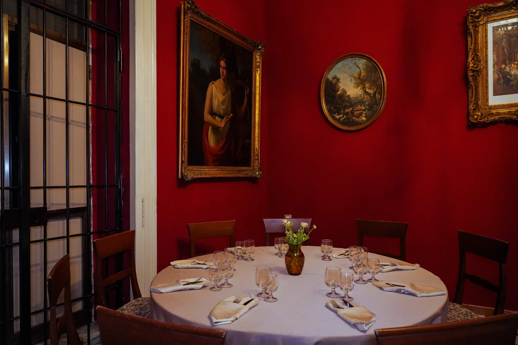 La sala rossa con i ritratti di famiglia e la tavola apparecchiata